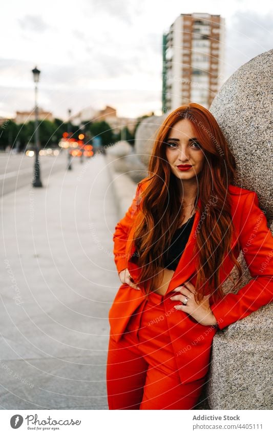 Content stylish redhead woman in suit in city orange style ginger bright color trendy female charming confident street fashion modern urban appearance long hair