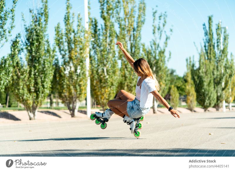 Woman balancing on one wheel in rollerblades and showing stunt woman balance trick equilibrium skater summer street female activity practice sunny sunlight