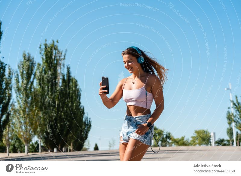 Smiling woman in rollerblades taking selfie in street smartphone city summer self portrait moment skater female happy cheerful music memory mobile device smile