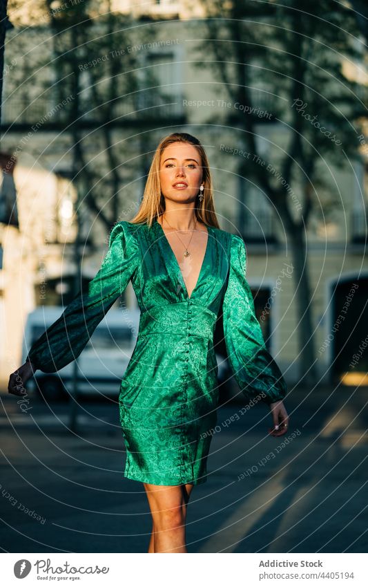 Carefree female in trendy green dress standing with outstretched arms in street and looking at camera woman fashion style carefree city freedom outfit summer