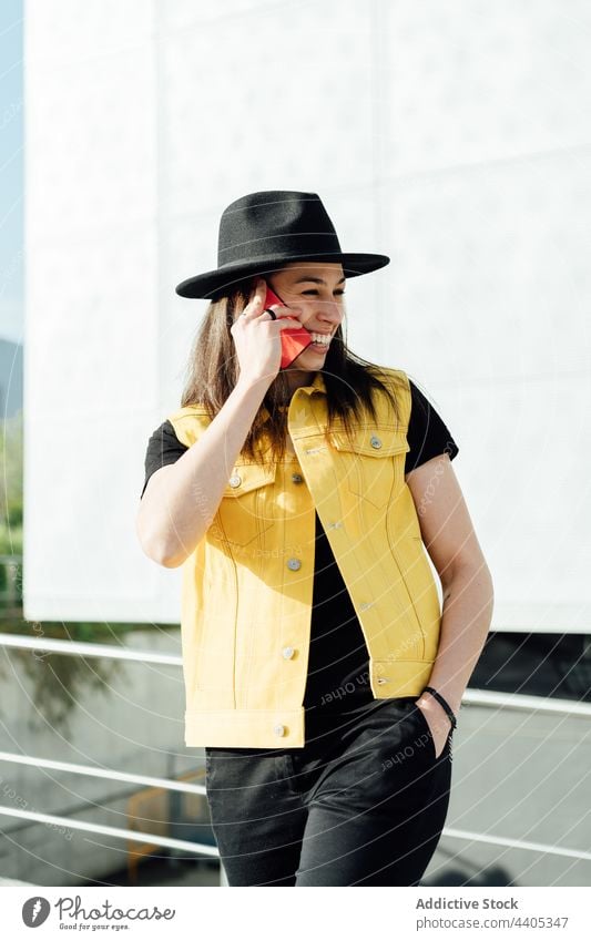 Cheerful woman speaking on smartphone in city talk sunny cheerful street cellphone conversation female gadget trendy device urban phone call charming stand