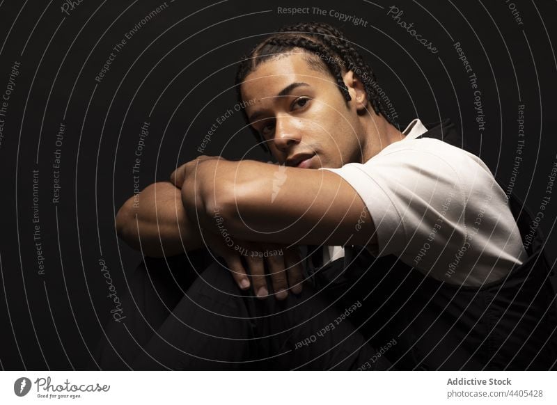 Young man with braids in dark studio style fashion afro confident model contrast hipster male ethnic black african american appearance young serious