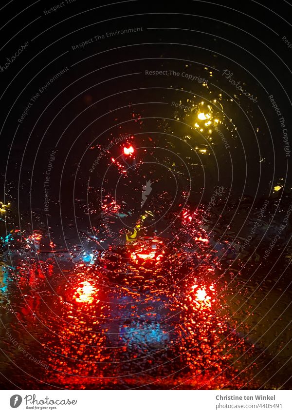 View through rain-soaked windscreen of illuminated cars waiting at traffic lights in darkness Rain Lights in the rain clearer Car lights Wet rainy Night Dark