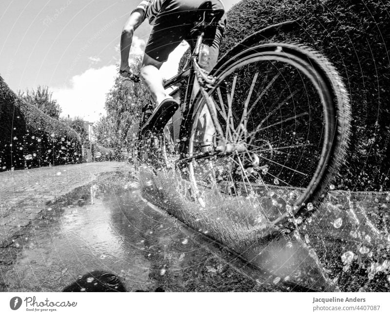Cyclist rides through a puddle activity blurriness Summer Leisure and hobbies Gray Lanes & trails Weather Exterior shot people Transport Healthy muck about