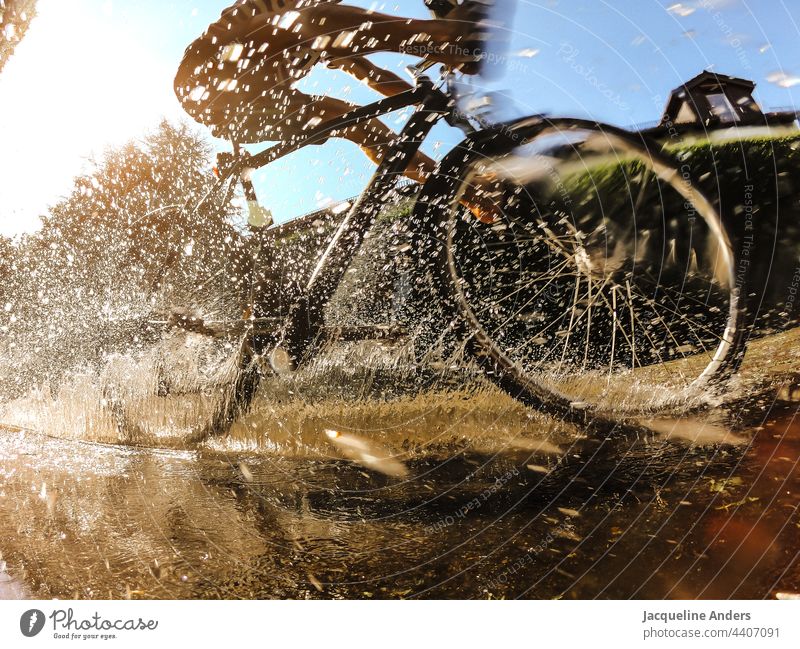Cyclist rides through a puddle in summer Bicycle Cycling cyclist Puddle reflection Inject Water Sports Street Transport Movement cyclists Outdoors Lifestyle