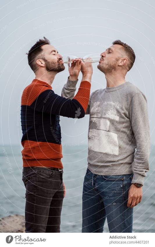 Couple of gays drinking champagne on sea shore beverage alcohol enjoy relationship romance glass seashore men couple lgbt spend time romantic ocean coast stand