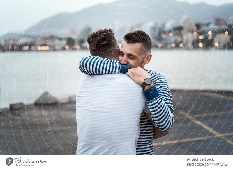 Homosexual couple embracing on pavement against city river embrace love relationship romantic lgbt sincere enjoy lake town highland mount affection bonding gay