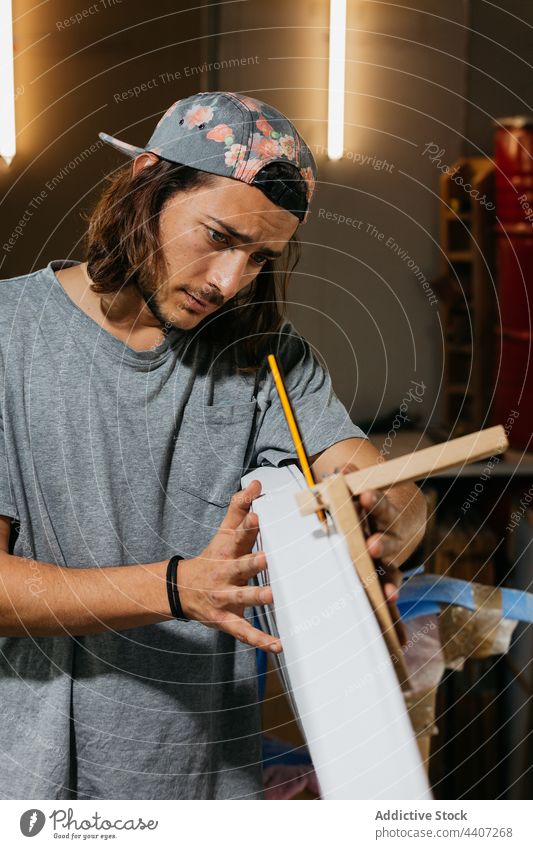 Focused male surfboard shaper suing scribe tool man mark pencil workshop hipster craftsman job occupation professional manual focus accuracy precise concentrate