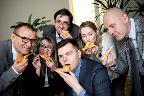 business, food, lunch and people concept - happy business team eating pizza in office finance friends sharing group meal businessmen businesswomen cheerful