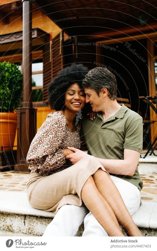 Loving multiethnic couple hugging on porch of house embrace together love stair cottage relationship multiracial diverse black african american happy cheerful