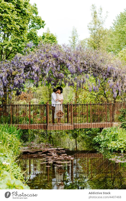 Couple embracing on bridge under arch with flowers couple hug garden park love embrace wisteria relationship romantic together nature tender bloom natural flora