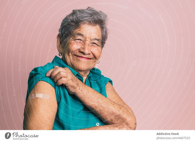 Aged woman with plaster on arm after vaccination from coronavirus aged vaccine patch smile cheerful senior health care female show demonstrate positive patient