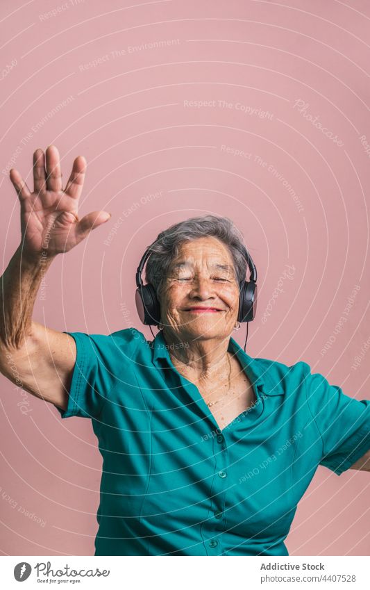 Happy elderly woman listening to music in headphones senior modern aged cheerful having fun dance female happy style audio sound enjoy device trendy positive