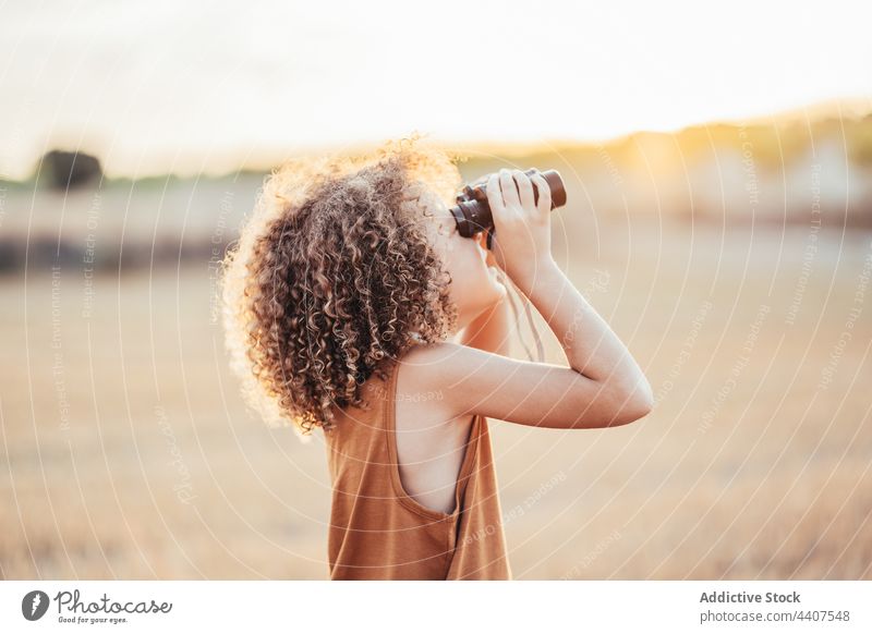 Happy ethnic kid looking through binoculars in field in summer child play game celebrate victory cheerful excited enjoy happy having fun carefree smile