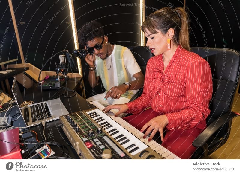 Diverse musicians working in record studio together play electric piano listen headphones multiracial multiethnic diverse black african american sound melody