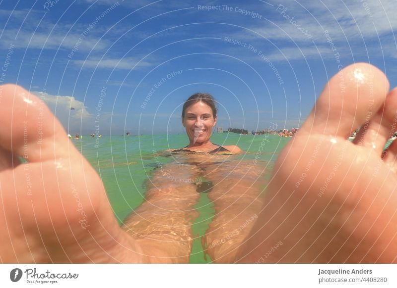 a woman is lying in the ocean in Florida with feet in the front Water florida Joy wave Swimming & Bathing USA Vacation & Travel Sunbeam Surf Sky Clouds Summer