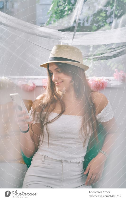 Smiling woman browsing smartphone in tent in backyard message social media using mobile smile content female gadget device communicate cheerful cellphone