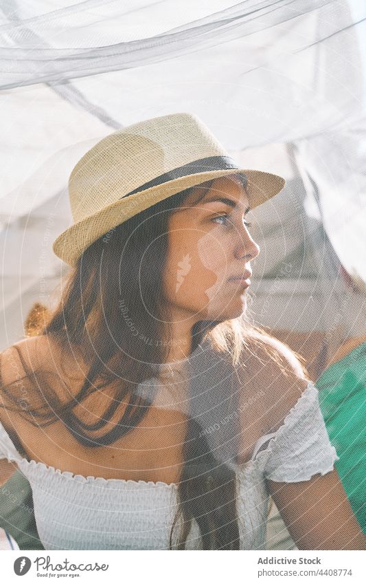 Young woman in sunhat sitting in tent summer content curtain young chill enjoy backyard female smile tranquil peaceful transparent serene harmony sunlight