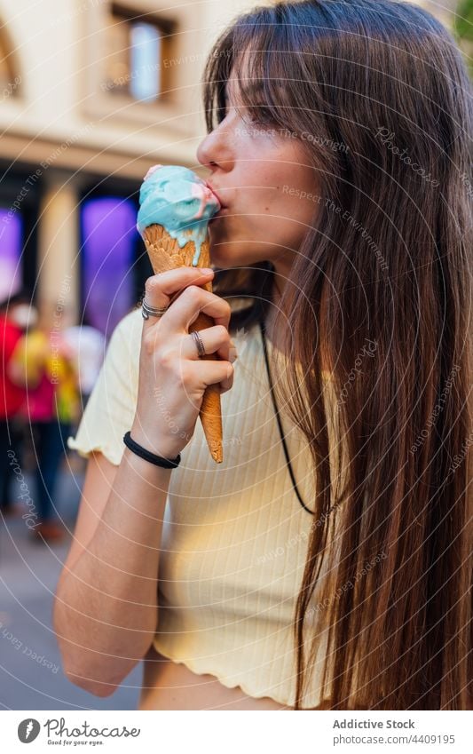 Crop woman enjoying delicious ice cream cone on street lick waffle dessert treat sweet crunchy gelato flavor pleasure tasty smile tongue out yummy smooth creamy