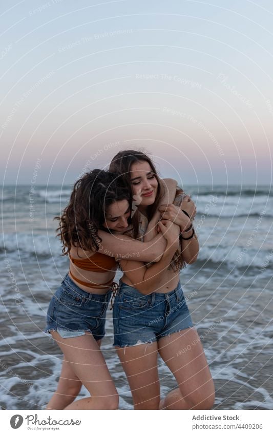 Happy lesbian couple embracing on beach women sea sundown hug love date female girlfriend romantic together sunset coast embrace relationship vacation summer