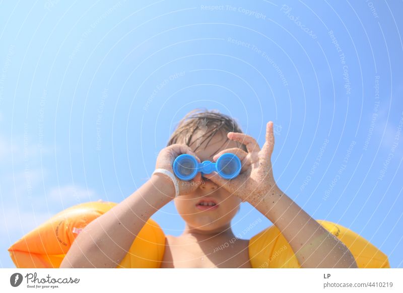 child looking through a toy binoculars outdoors looking away observe positive shore freedom vacation seaside enjoying carefree childhood casual cute day