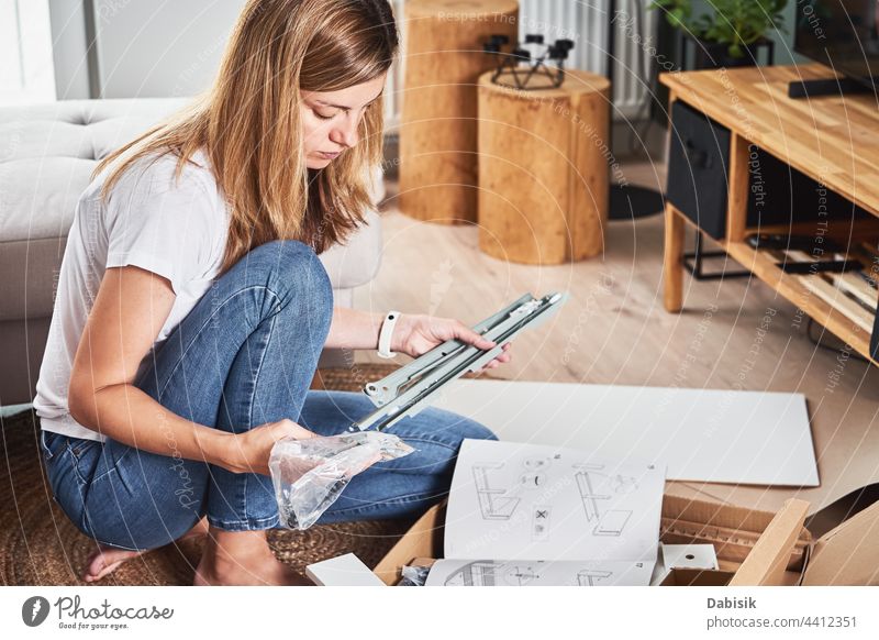Woman reading manual instruction to assemble furniture woman assembling diy people interior apartment assembly box caucasian equipment fix fixing floor home
