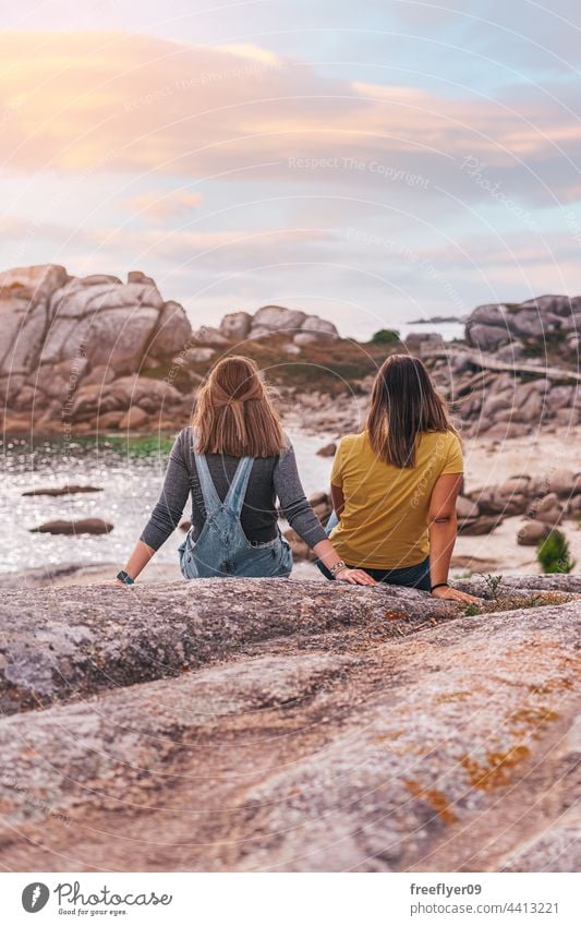 Two female friends contemplating the ocean copy space contemplation sunset oceanside rocks coastline mediterranean caucasian friendship sea vacation young woman