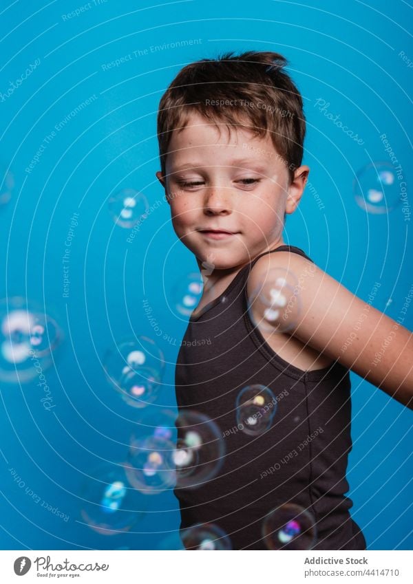 Child looking away in studio with soap bubbles child boy kid surprise childhood face expression wow reaction sign symbol indicate virtual display click cute