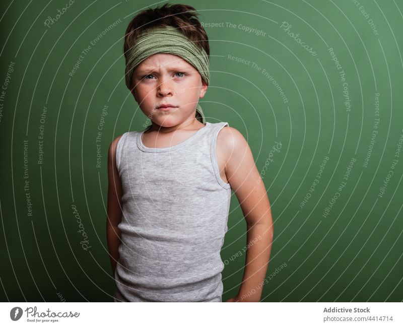 Playful karate child standing on green background portrait play game boy cheerful having fun reach out serious clench fist kid happy childhood preteen hachimaki