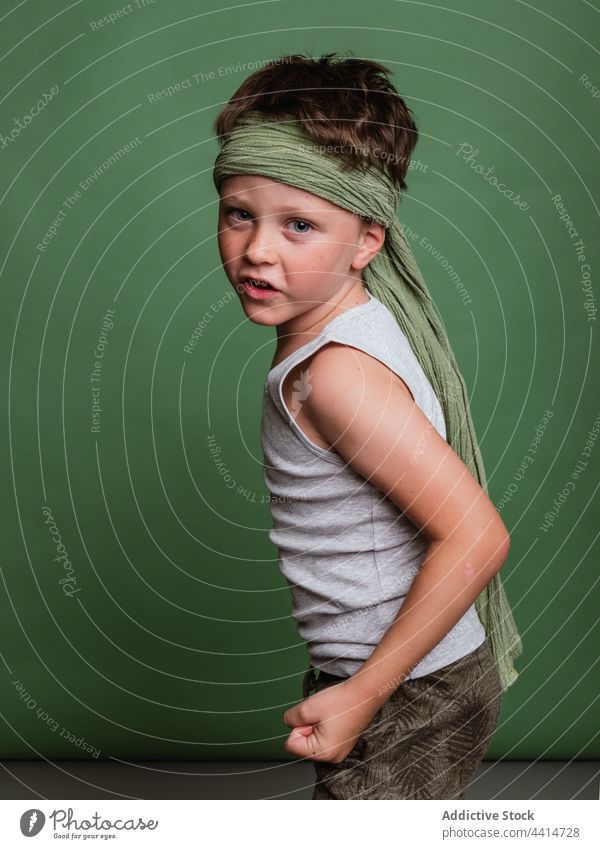 Playful karate child standing on green background play game boy cheerful having fun reach out clench fist kid happy childhood preteen hachimaki headscarf