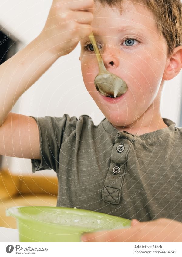 Child with spoon eating cream soup child lick lunch boy meal food home kid dish tasty kitchen cute yummy cuisine nutrition healthy appetite adorable delicious