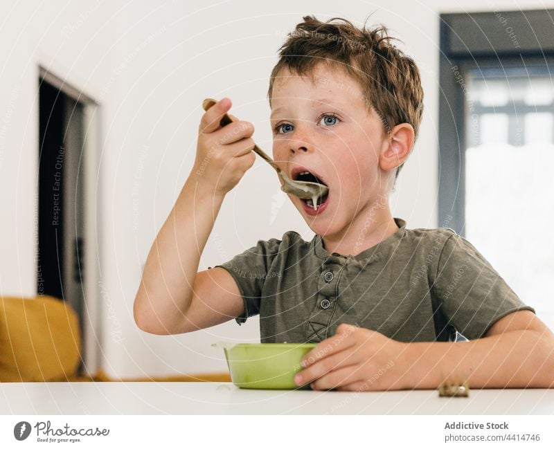 Child with spoon eating cream soup child lick lunch boy open mouth meal food home kid dish tasty kitchen cute yummy cuisine nutrition healthy appetite adorable