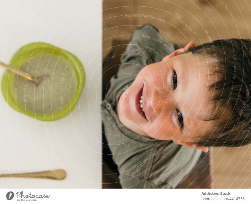 Child sitting at table at lunch time child eat portrait spoon cream soup boy meal food home kid dish tasty kitchen cute yummy cuisine nutrition healthy appetite