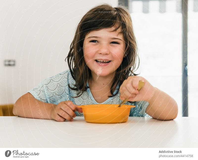 Funny girl eating cream soup during lunch child kid home delicious puree bowl table food meal childhood healthy nutrition cute yummy dish tasty spoon kitchen