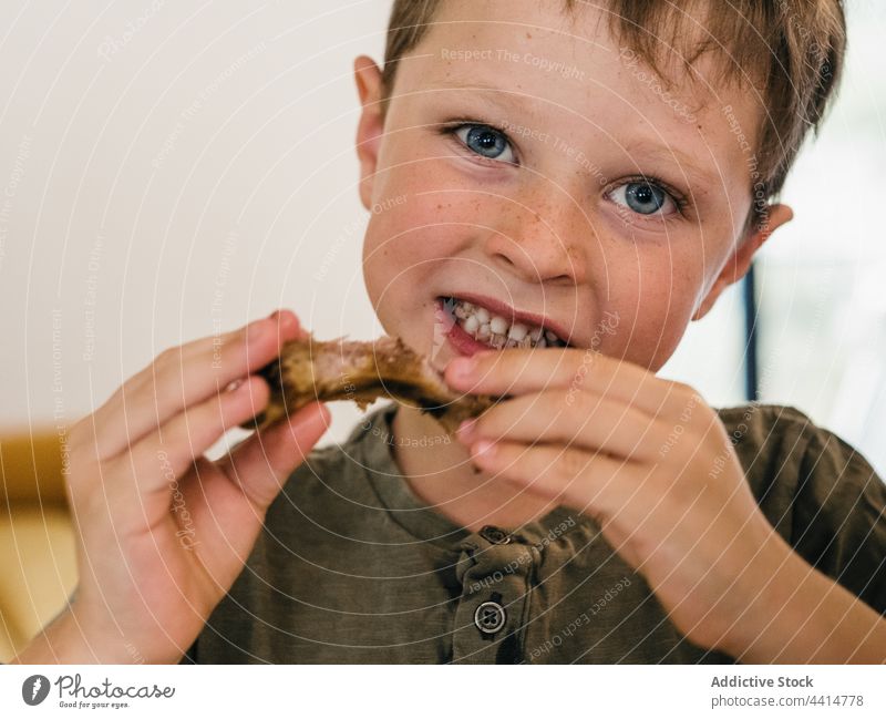 Hungry child eating pork ribs during lunch home food boy kid appetizing cute meal adorable enjoy tasty delicious nutrition domestic childhood homemade fresh