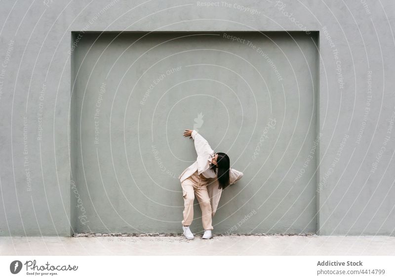 Talented woman dancing against gray wall in city dance dancer street energy style urban cool female talent flexible move choreography lean bend grace skill