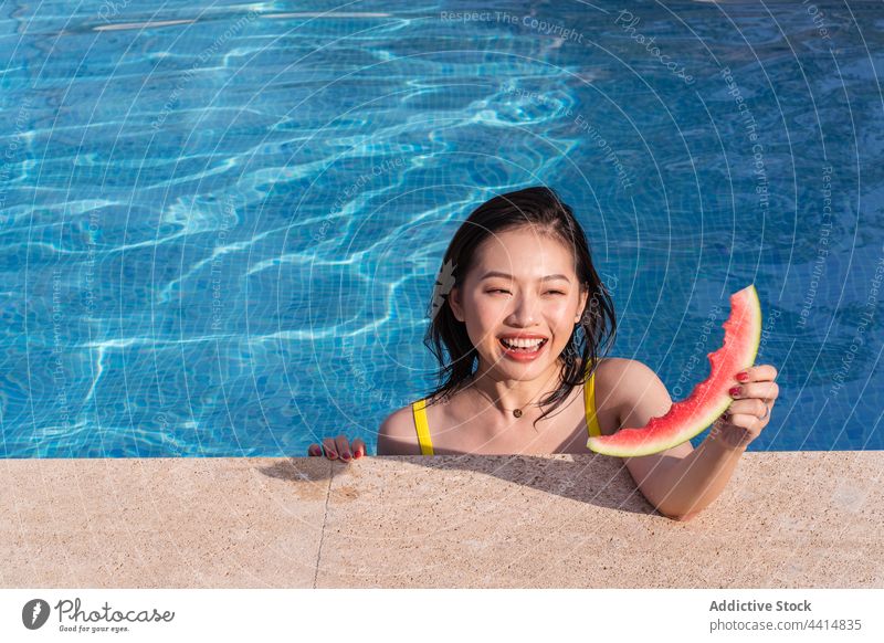 Content Asian woman in swimming pool with watermelon summer enjoy happy resort vacation female ethnic asian fresh summertime weekend cheerful slice young