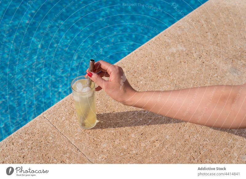 Crop woman with glass of cold cocktail at poolside women refreshment summer drink sunny zero waste beverage female water sunlight ice cube cool eco friendly