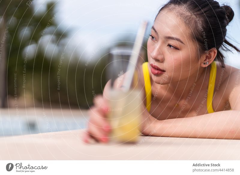 Ethnic woman in bikini sunbathing at poolside in summer suntan lying vacation chill female holiday enjoy ethnic asian yellow color bright vivid vibrant