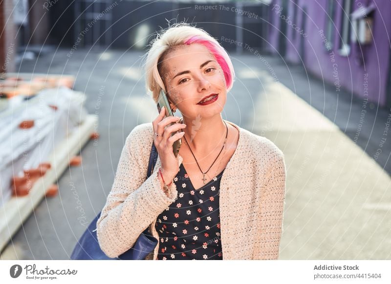 Smiling informal woman talking on smartphone in city alternative speak smile subculture conversation female mobile cheerful call gadget urban style young