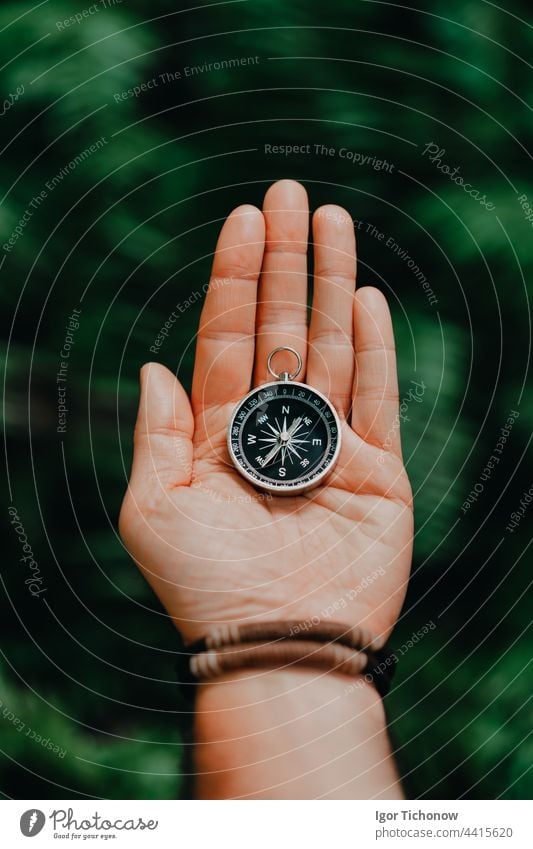 Hand with compass against tropical forest jungle terrain. POV Travel concept background hand person sport vintage summer man nature technology lost tourism