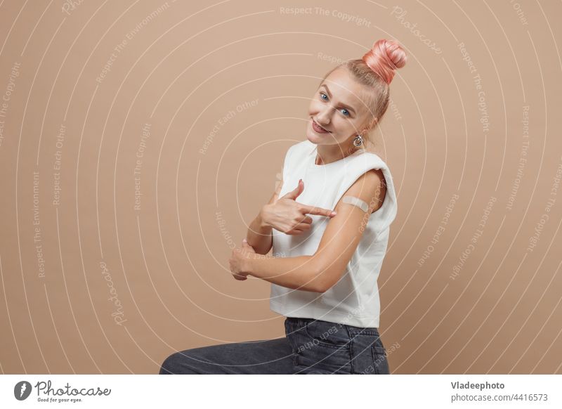 Young hipster woman with patch after coronavirus covid 19 vaccination. Covid vaccination concept, monochrome background COVID Immunization vaccine injection Arm