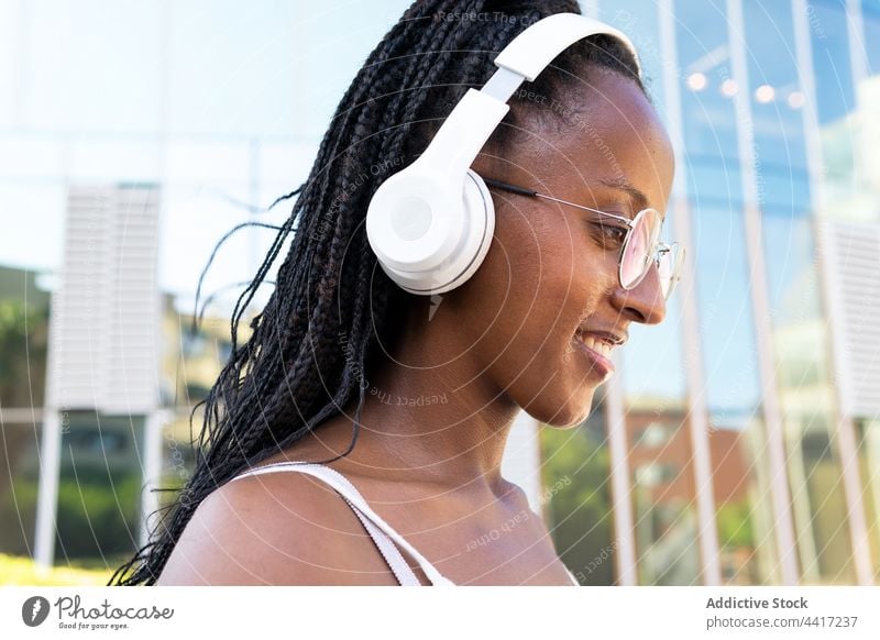 Happy black woman listening to music in headphones in city white color cheerful song enjoy female ethnic african american barceloneta barcelona spain using