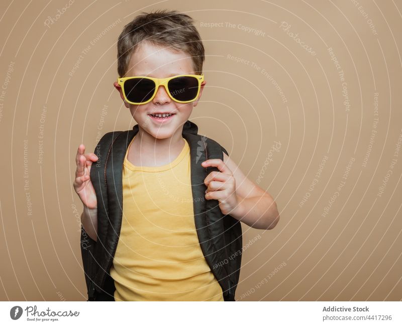 Smiling pupil with backpack and in sunglasses in studio child kid boy cool schoolboy schoolchild smile cheerful happy positive childhood glad optimist style