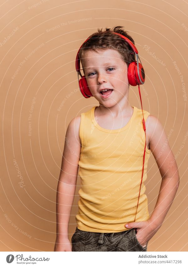 Cheerful child listening to music in headphones and singing song enjoy preteen boy entertain studio kid device gadget sound style cool amusement talent audio