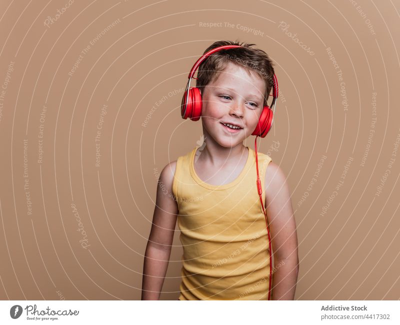 Cheerful child listening to music in headphones song enjoy preteen boy entertain studio kid device gadget sound style cool amusement talent audio childhood