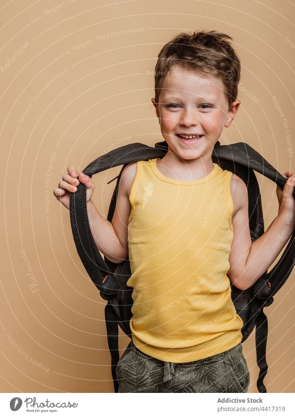 Smiling pupil with backpack in studio child kid boy cool schoolboy schoolchild smile cheerful happy positive childhood glad optimist style toothy smile rucksack