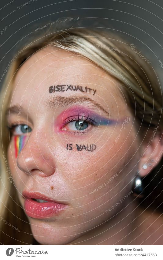 Young lesbian woman with bright makeup looking at camera lgbtq homosexual bisexual pride flag rainbow tolerance inscription bisexuality is valid gay liberty