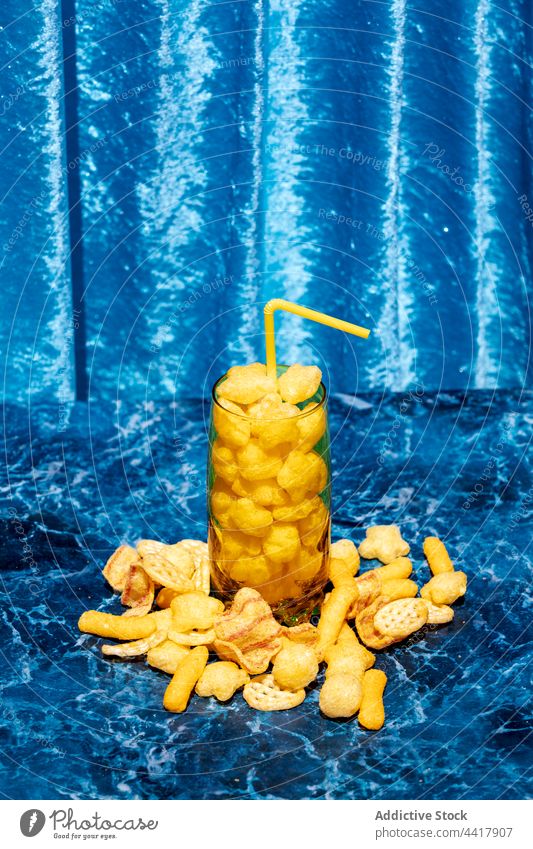 Glass with cereal on table in studio glass cocktail corn stick concept creative refreshment drink straw tasty delicious sweet nutrition art snack bright color