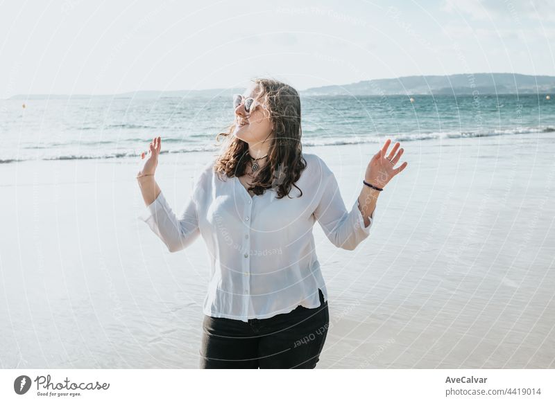Happy young woman laughing and smiling at the beach on a summer day, enjoying vacation, concept of friendship enjoying the outdoor happiness arm carefree